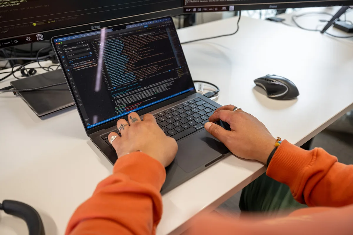 Laptop met code-editor, close-up van handen typend