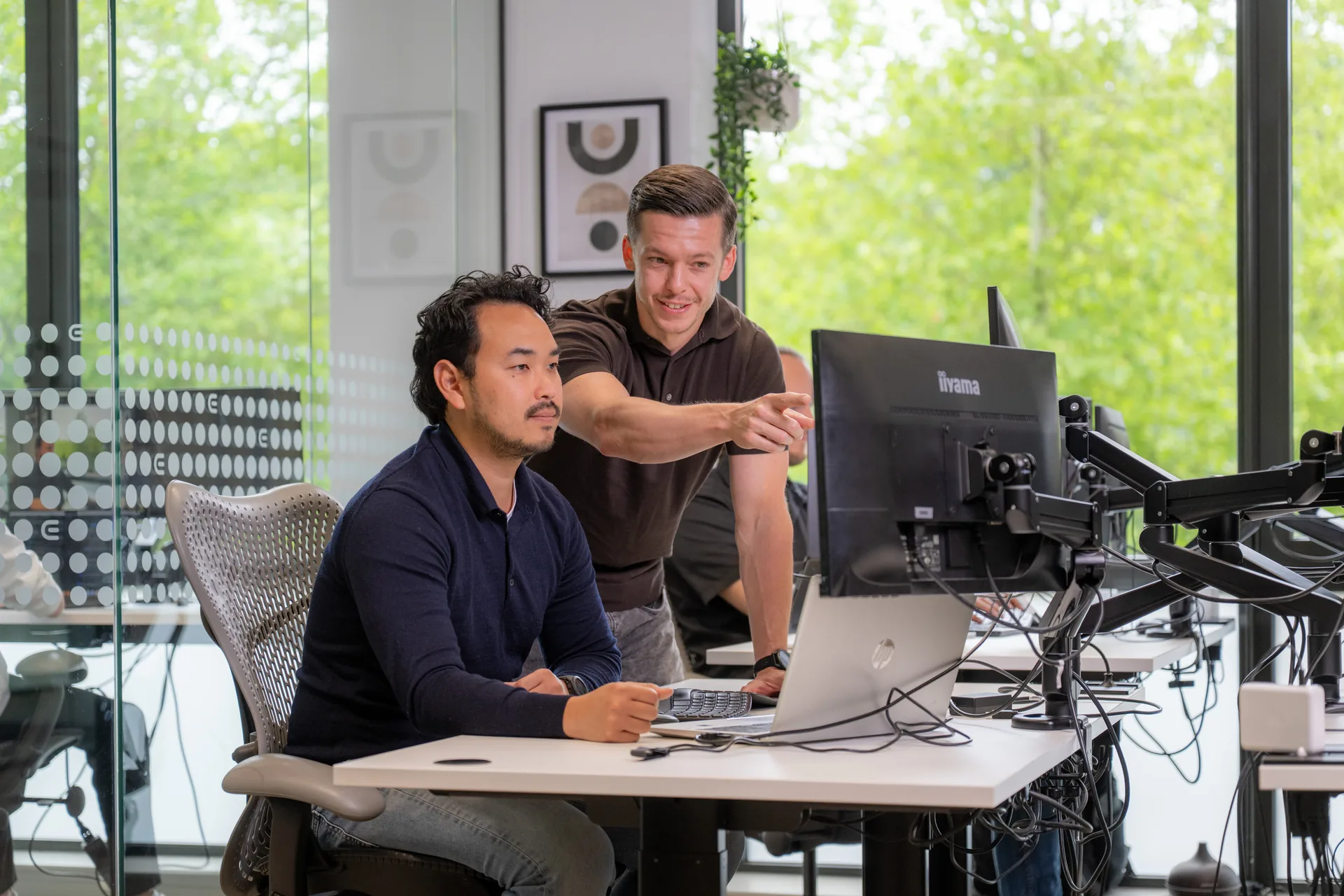 Twee Emendis-ontwikkelaars kijken samen naar code op een monitor