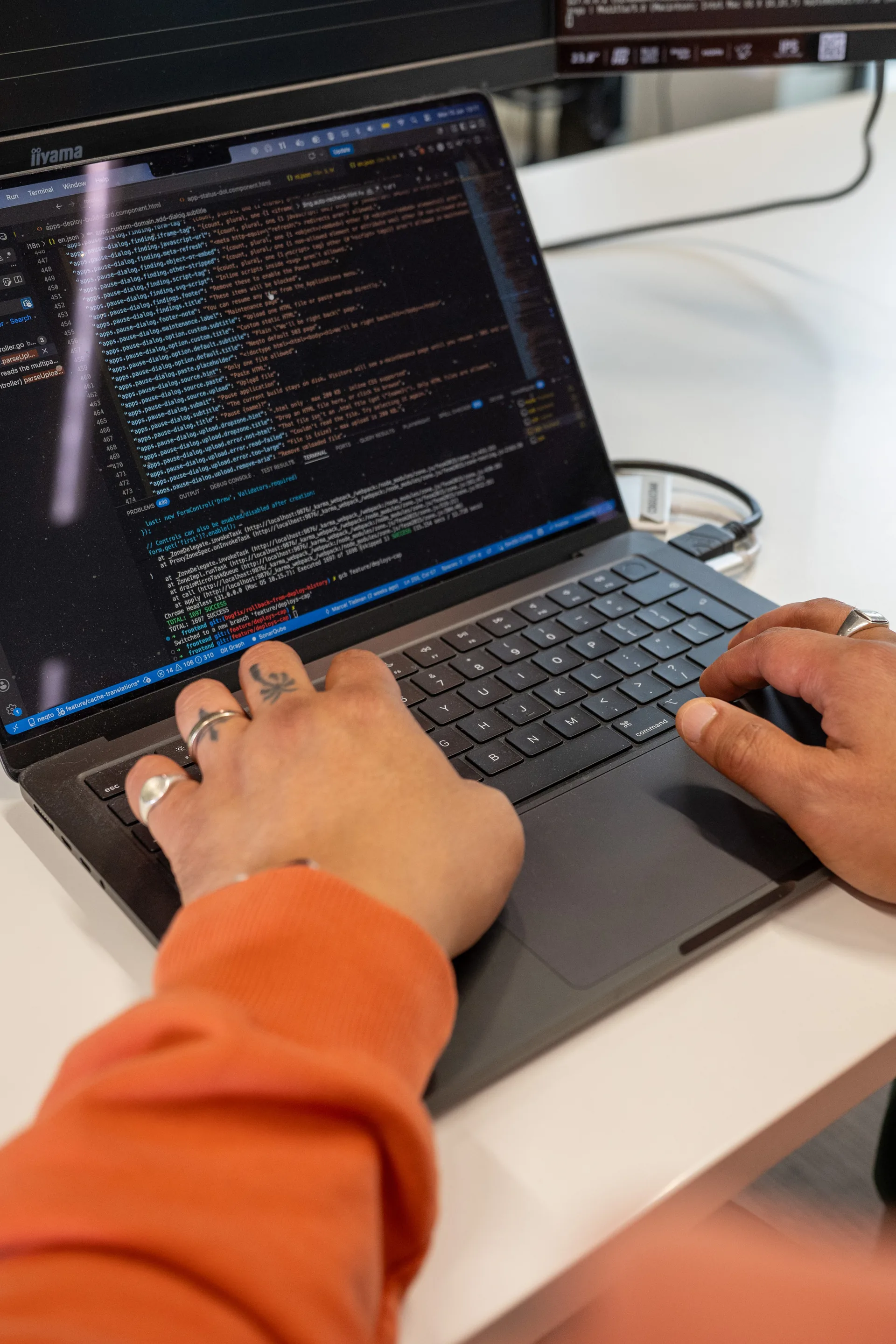 Handen typend op een MacBook met code-editor open