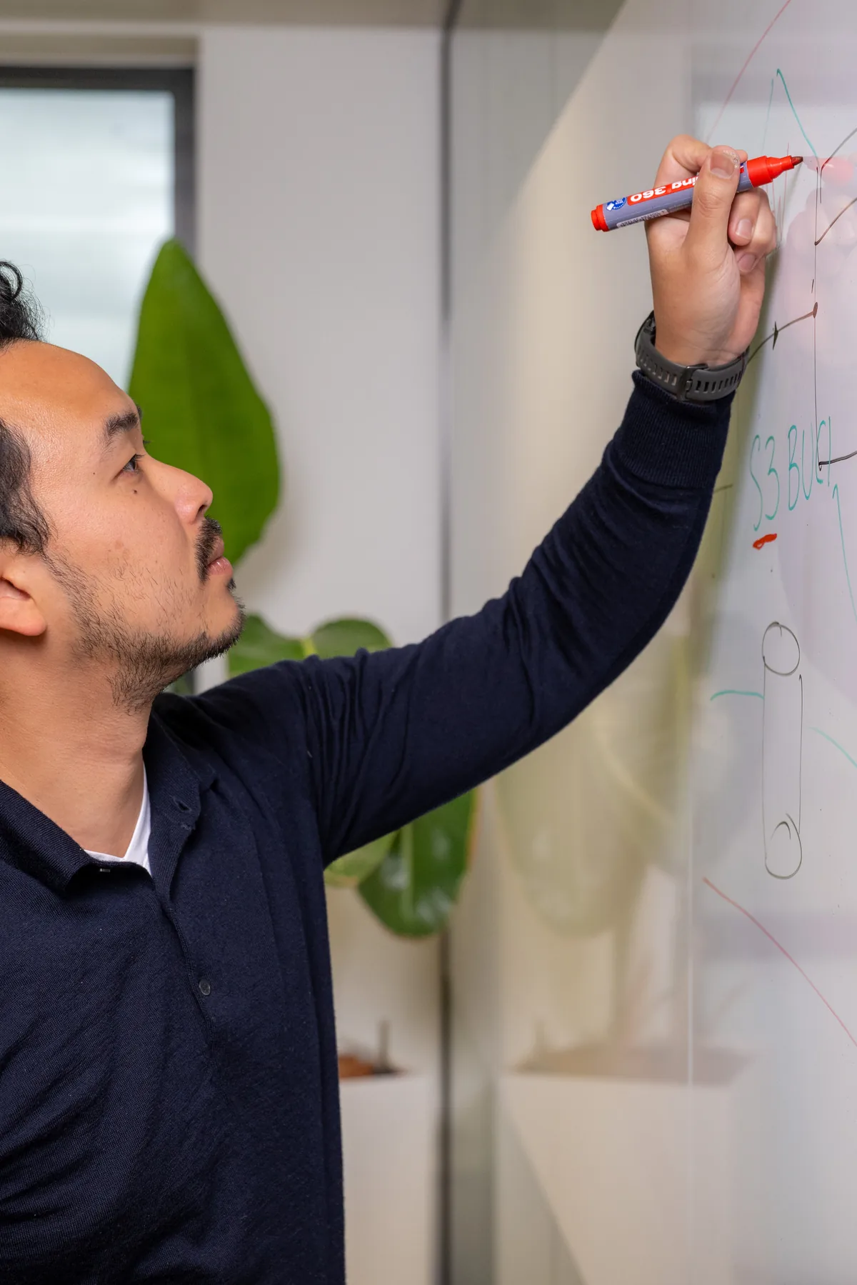 Emendis-medewerker in oranje trui werkt een idee uit op het whiteboard