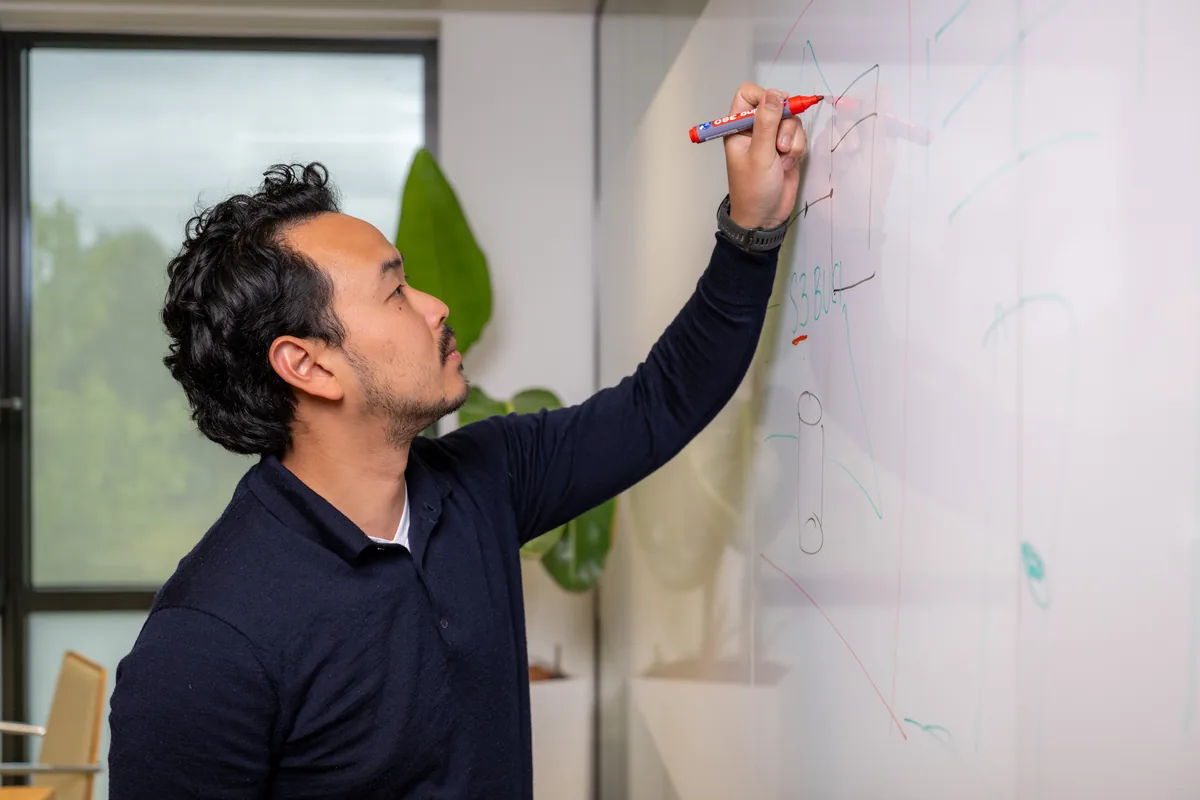 Emendis-medewerker schrijft geconcentreerd op het whiteboard